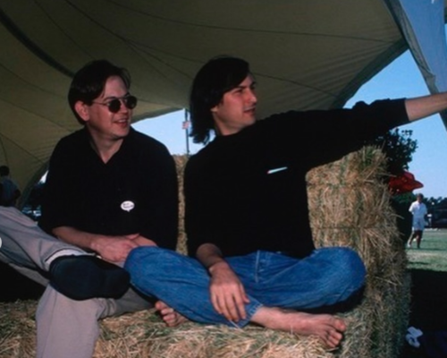 Steve Jobs sitting barefoot with colleague at outdoor gathering